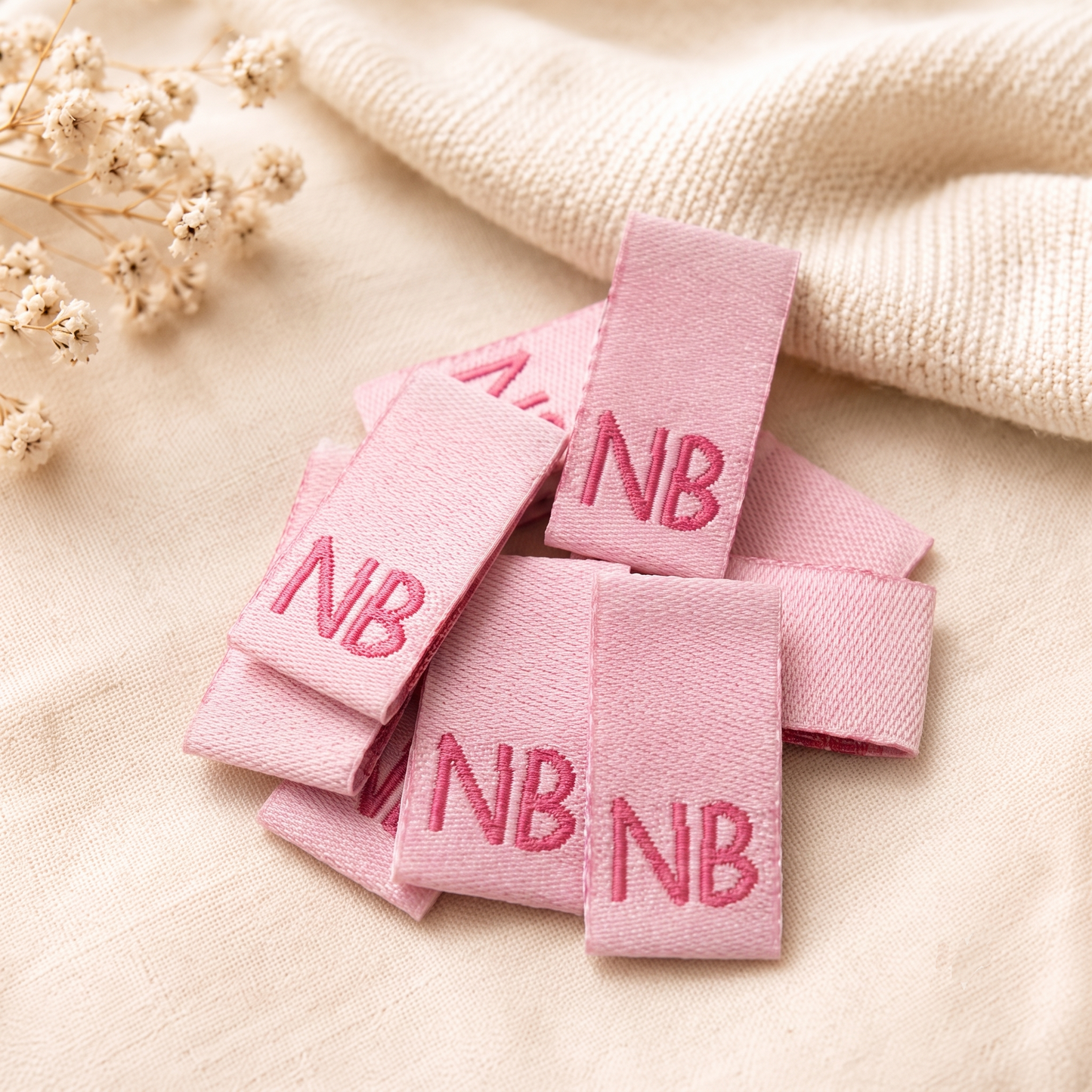 Pink custom woven labels with NB lettering for clothing, garments and handmade products